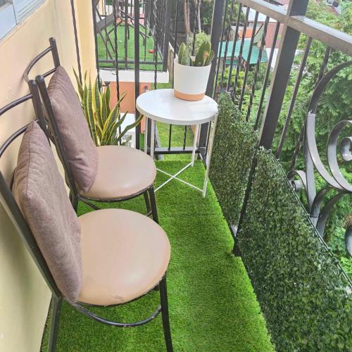 two chairs and a table on a balcony with grass at Arezzo Place Davao-Rental in Davao City