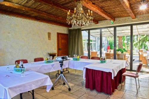 a dining room with two tables and a chandelier at Ringhotel Alpenhof - Patchworkhotel in Augsburg