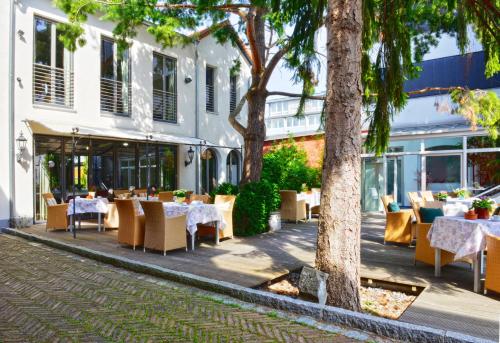 a restaurant with tables and chairs in front of a building at Ringhotel Alpenhof - Patchworkhotel in Augsburg