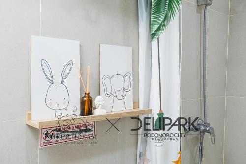 a shelf in a bathroom with three pictures of rabbits at Delipark Mall 3 Bedrooms 3 Bathrooms 8-10 Pax Empire Premium Tower Level 28 in Medan