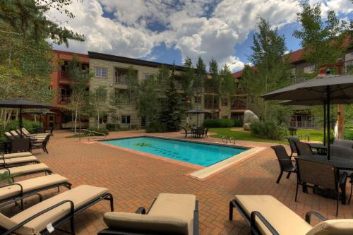 a pool with chairs and umbrellas next to a building at Expedition 8631 in Keystone