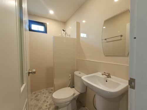 a white bathroom with a toilet and a sink at Ban Suan Kun Parn Khao Yai in Mu Si