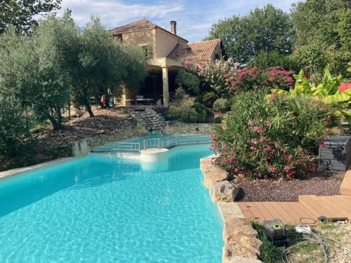 une grande piscine bleue devant une maison dans l'établissement Villa Luna avec piscine dans un parc de 5200M en plein cœur du Périgord Noir, à Mauzens-et-Miremont