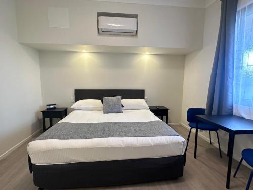 a bedroom with a bed and a blue chair at Puffers Inn in Loganholme