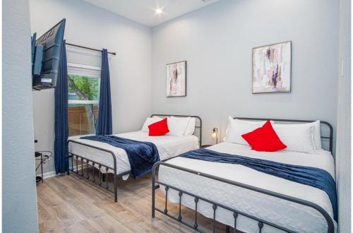 2 Betten mit roten Kissen in einem Zimmer in der Unterkunft Seize the Moment 4BR3BA Gem w Downtown Views in San Antonio