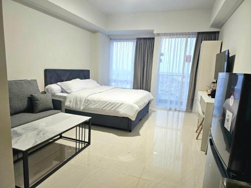 a bedroom with a bed and a couch and a tv at Green Sedayu Apartment Family Suite by Ellison in Jakarta