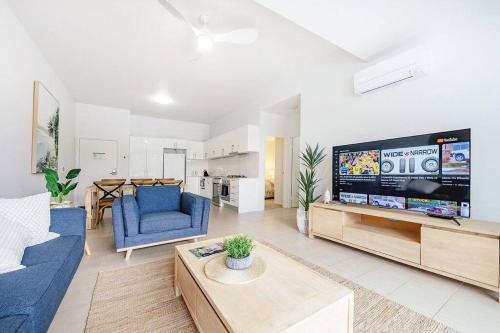 a living room with a blue couch and a tv at Stay Seaside Market 416 in Woolgoolga