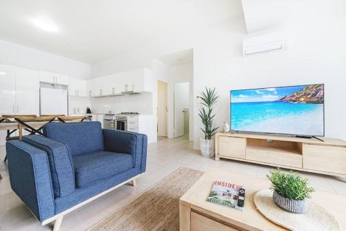 a living room with a blue couch and a tv at Stay Seaside Market 416 in Woolgoolga