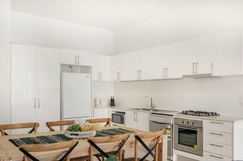 a white kitchen with a table and chairs in it at Stay Seaside Market 416 in Woolgoolga