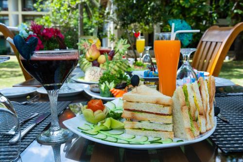 a table with a plate of sandwiches and a glass of wine at Oak Ray Elephant Lake in Sigiriya