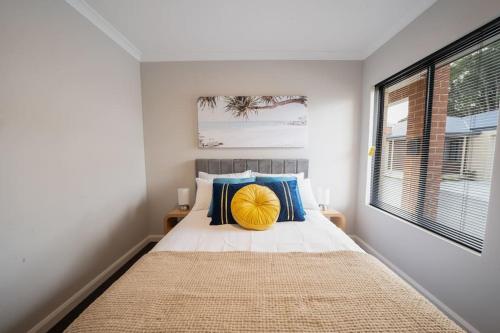 a bedroom with a bed with blue and yellow pillows at Convinient Cosy home with all around you! in Kelmscott