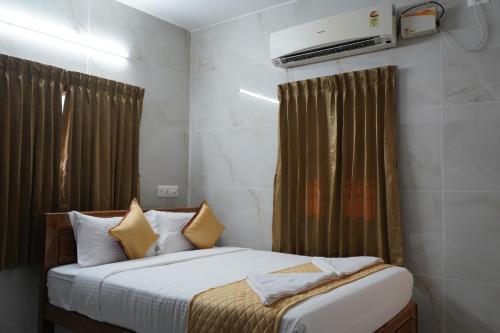 a bedroom with a bed with white sheets and yellow pillows at Golden Dawn Residency in Tiruvannāmalai