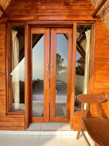 a glass door on a wooden house with a chair at Bali Sunrise Camp & Glamping in Kintamani