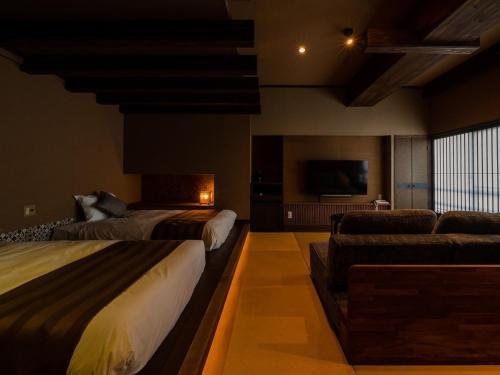 a hotel room with two beds and a couch at Unzen Fukudaya in Unzen