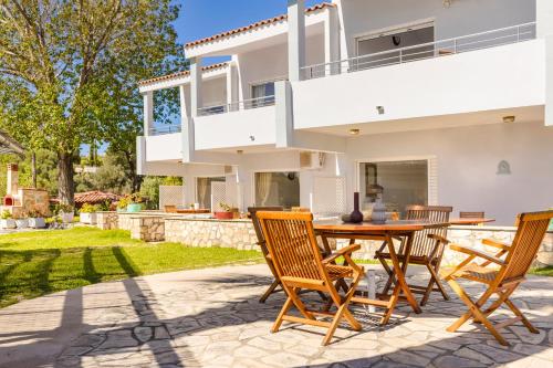 a patio with a wooden table and chairs in front of a house at Costa Avithos in Svoronata