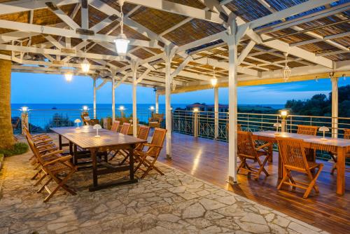 a patio with tables and chairs and a view of the ocean at Costa Avithos in Svoronata