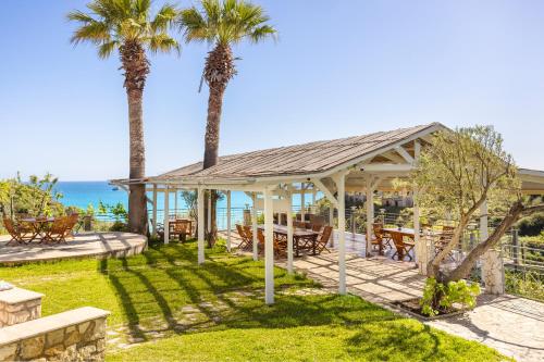a pavilion with palm trees and the ocean in the background at Costa Avithos in Svoronata