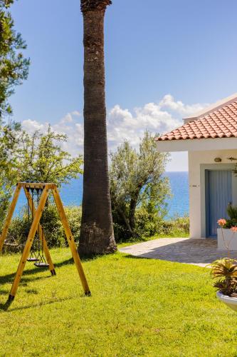 a wooden swing in the grass next to a house at Costa Avithos in Svoronata