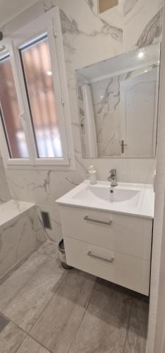 une salle de bain blanche avec un lavabo et un miroir dans l'établissement Newly renovated 5min beach & 2min train station, à Vallauris