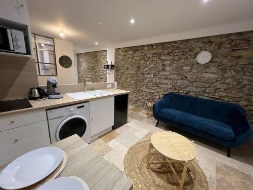 - un salon avec un canapé bleu et un mur en pierre dans l'établissement Le Merveilleux Voyage, Clim, à Carcassonne