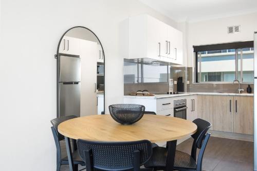 a kitchen with a wooden table and chairs in a kitchen at Ocean Spray 8 in Coffs Harbour
