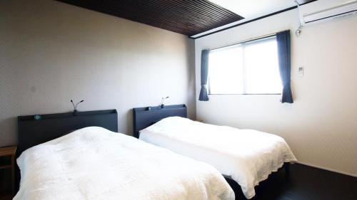 two beds in a room with a window at DO PI-CAN in Motobu