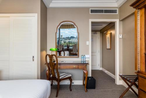 a bedroom with a desk with a mirror and a bed at Stamford Plaza Brisbane in Brisbane