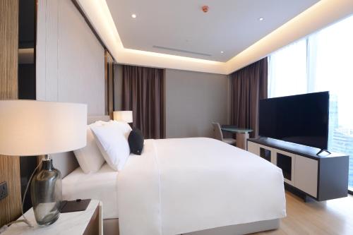 a bedroom with a white bed and a flat screen tv at Imperial KLCC by Opus Hospitality in Kuala Lumpur