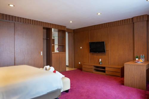 a bedroom with a bed and a flat screen tv at Favor Hotel Pekanbaru City Center in Pekanbaru