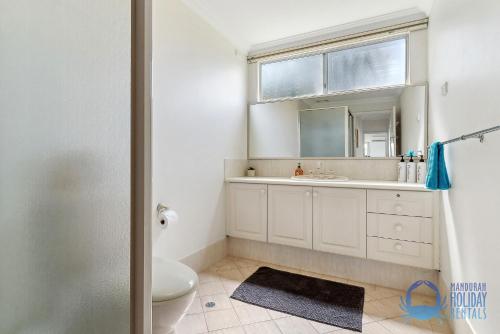 a bathroom with a toilet and a sink and a mirror at Mandurah Overlooking The Marina in Mandurah