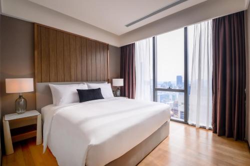 a bedroom with a large white bed and a large window at Imperial KLCC by Opus Hospitality in Kuala Lumpur
