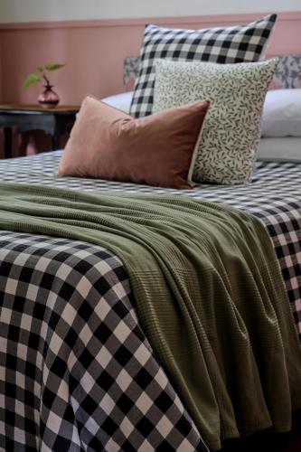 a bed with black and white checked sheets and pillows at Poppy's Place - Denmark in Denmark