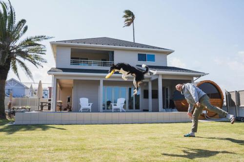 a man playing frisbee with a dog in front of a house at SEADINERS Beachfront Villa 99 in Ichinomiya