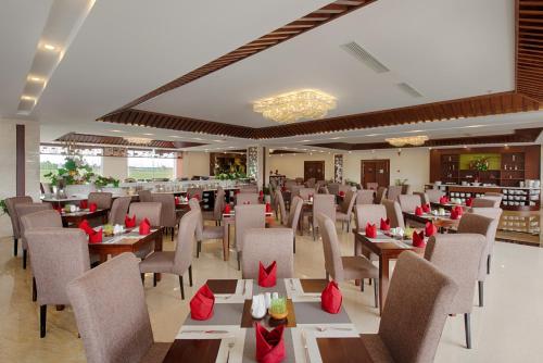 a restaurant with tables and chairs with red bows at Muong Thanh Holiday Hoi An Hotel in Hoi An