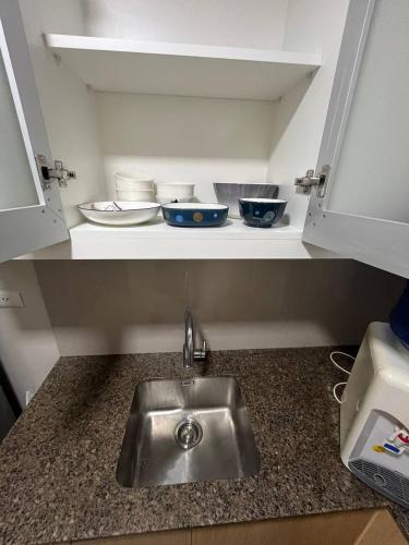 a kitchen counter with a sink and bowls on a shelf at GENTRY MANOR fast WiFi,Balcony near Okada,MOA&NAIA 8Q in Manila