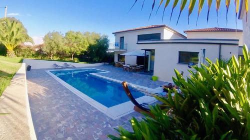 une maison avec une piscine devant une maison dans l'établissement Villa jardin tropical, à Afa