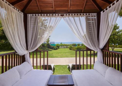 a screened in porch with white curtains and a view of a yard at Akra Sorgun Tui Blue Sensatori - Ultra All Inclusive in Side