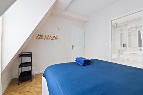 - une chambre blanche avec un lit bleu et un lavabo dans l'établissement Appartement Quartier Rue de la Paix Free Netflix, à Paris