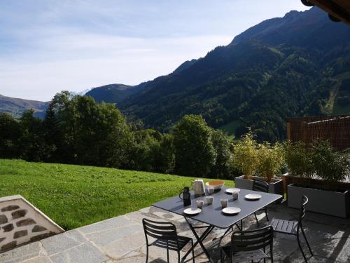 a table and chairs on a patio with mountains in the background at La ferme d'Hauteluce - Chalets in Hauteluce