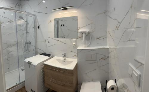 a white bathroom with a sink and a shower at Apartament Magdalenka in Strzelce Opolskie