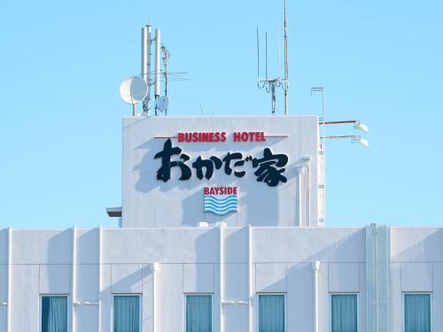 a white building with a sign on the side of it at Business Hotel Okadaya Bayside in Toyohashi