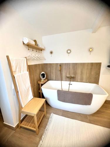 La salle de bains est pourvue d'une baignoire blanche, d'une chaise et d'une chaise. dans l'établissement Les jardins de Funtanone, à Vignale