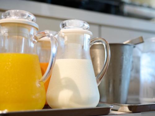 two glass containers of milk and orange juice on a counter at Business Hotel Okadaya Bayside in Toyohashi