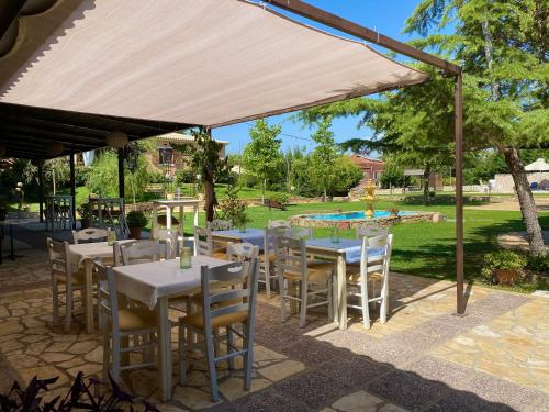 a patio with tables and chairs under a tent at Evilion Ktima Argyropoulou in Katarrákhion