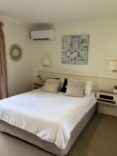a bedroom with a large bed with white sheets and pillows at Casa Palma in Palm Cove
