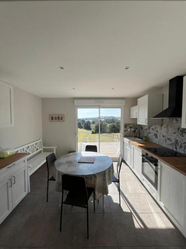 une cuisine avec une table et des chaises dans une cuisine dans l'établissement Gites de Landuzire, Sleeps 14, à Saint-Genest-Lerpt