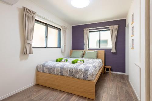 a bedroom with a bed with purple walls and windows at Ici Japon Village in Tokyo