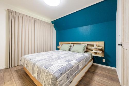 a bedroom with a blue accent wall and a bed at Ici Japon Village in Tokyo