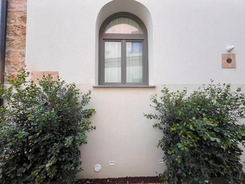 a window on the side of a building with two bushes at Spasimo Hôtellerie in Palermo
