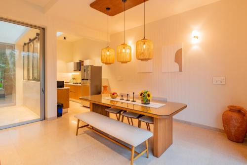 a kitchen with a table and a bench and lights at ELIVAAS 3 BHK with Pvt Pool & Spacious living Area - Mirai Villa Sukoon in Old Goa